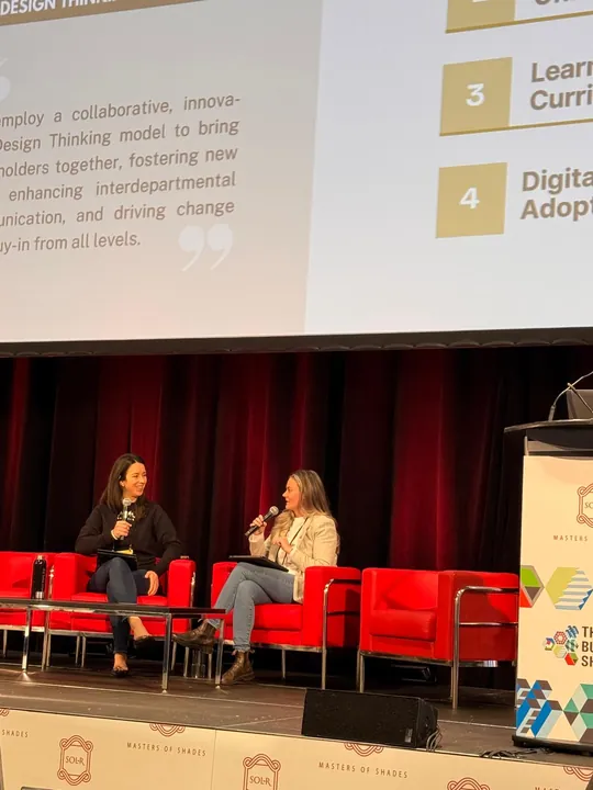 A panel on stage with slides on learning curriculum and digital adoption