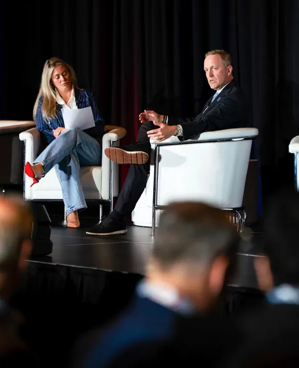 Two speakers in conversation on stage, audience in the foreground