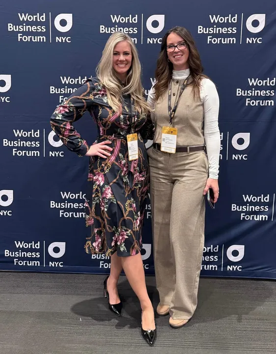 Two speakers at the World Business Forum NYC backdrop
